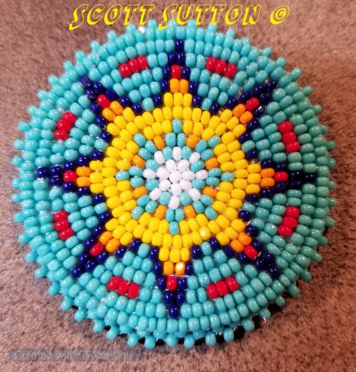 a colorful beaded brooch sitting on top of a brown carpet next to a wall