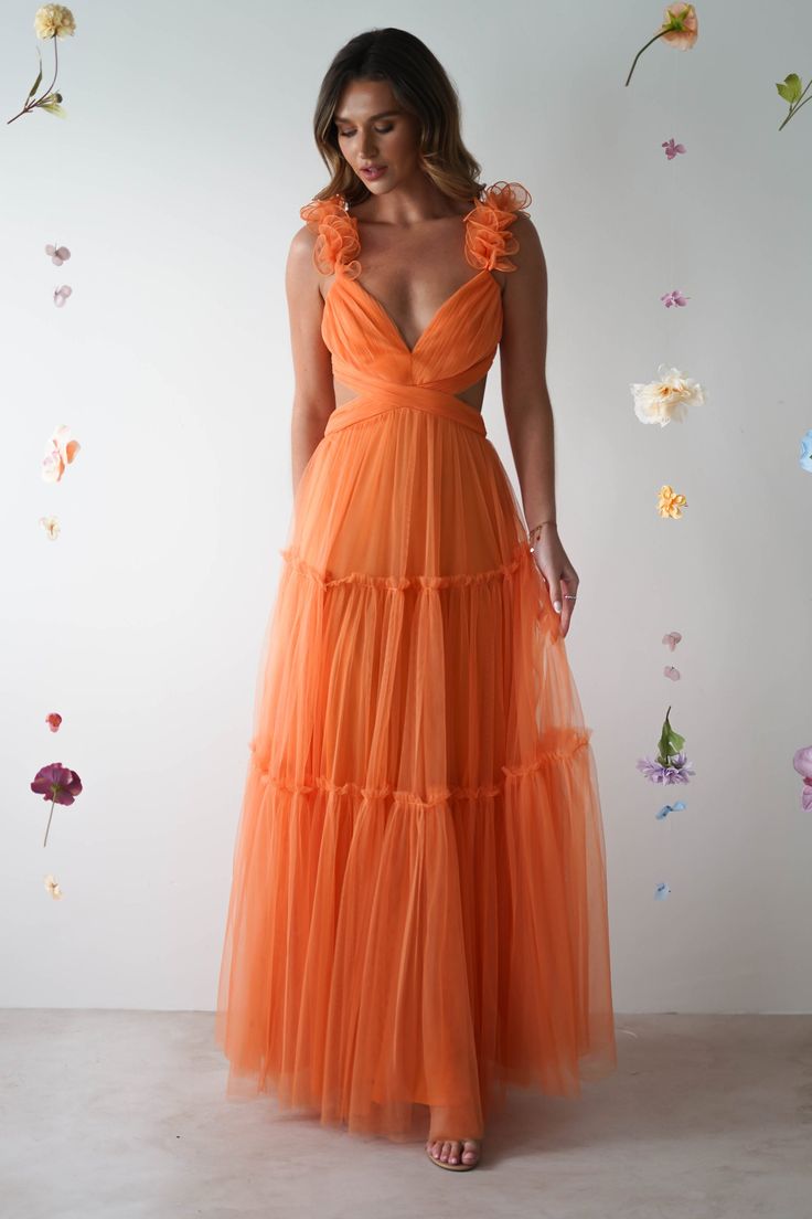 a woman in an orange dress standing next to flowers