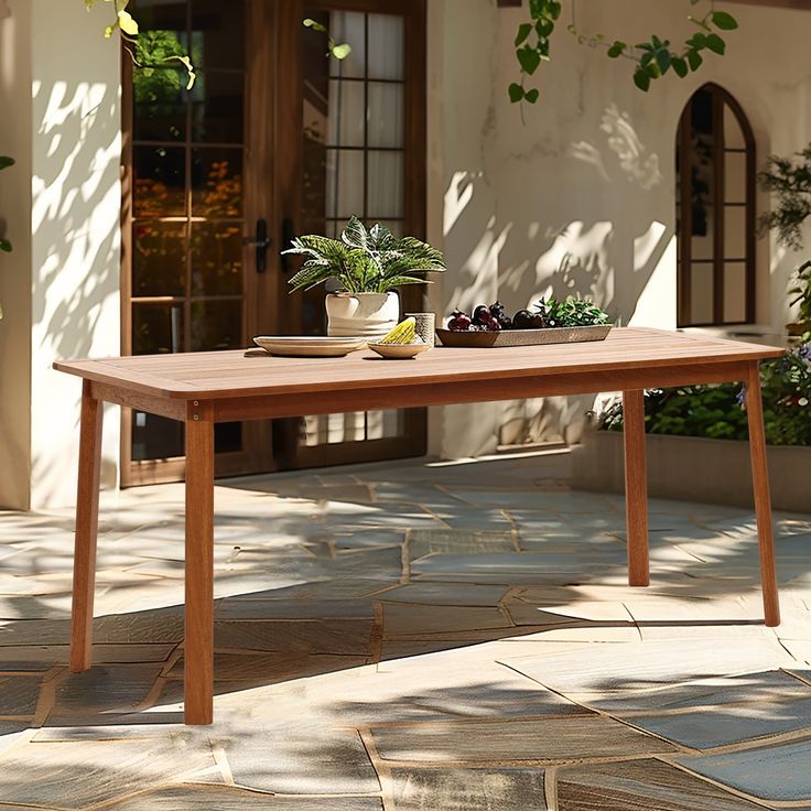 a wooden table sitting on top of a stone floor next to potted planters