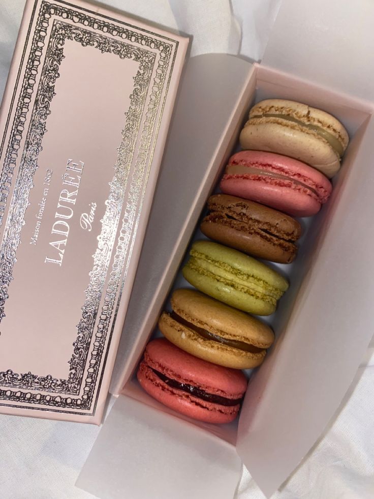 a pink box filled with different colored macaroons