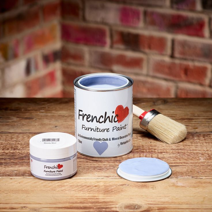 a paint can with a brush next to it and some other paints on a wooden table