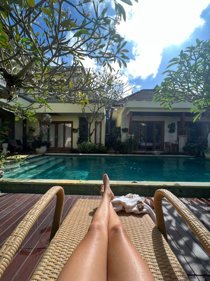 a person laying down in front of a swimming pool with their feet on the ground