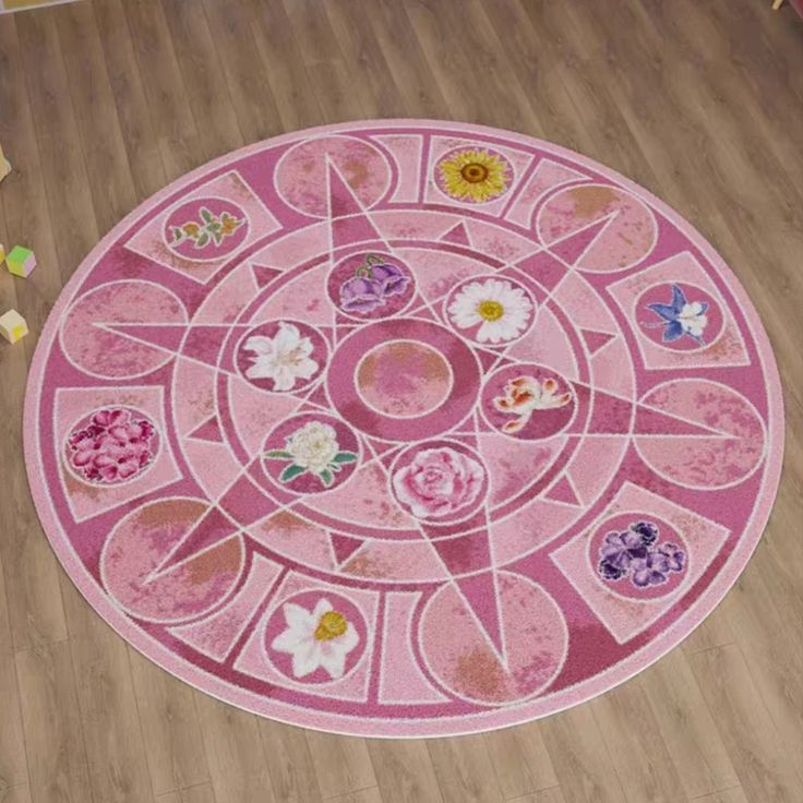 a pink circular rug with flowers and butterflies in the center on a wooden floor next to a child's toy