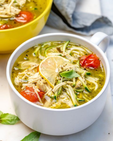 two bowls filled with soup and garnished with lemons, tomatoes and herbs