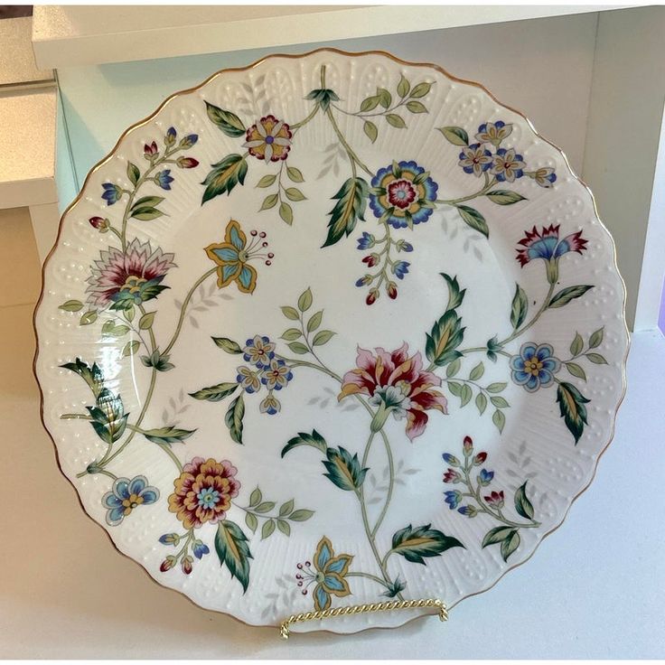 a decorative plate with flowers and leaves painted on it's side, hanging from the wall