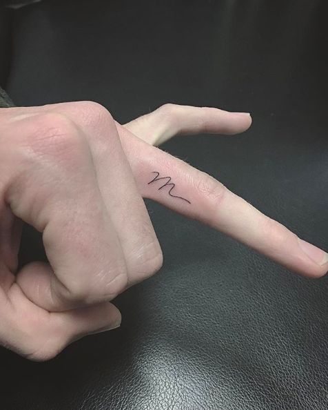 a person's hand with a small tattoo on it, pointing to the left