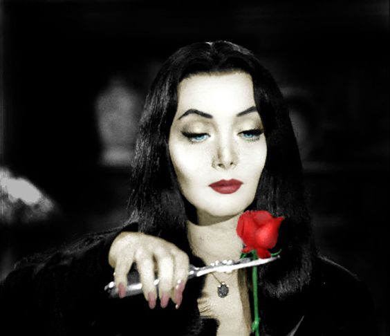 a woman holding a rose in her right hand and looking at the camera with an evil look on her face