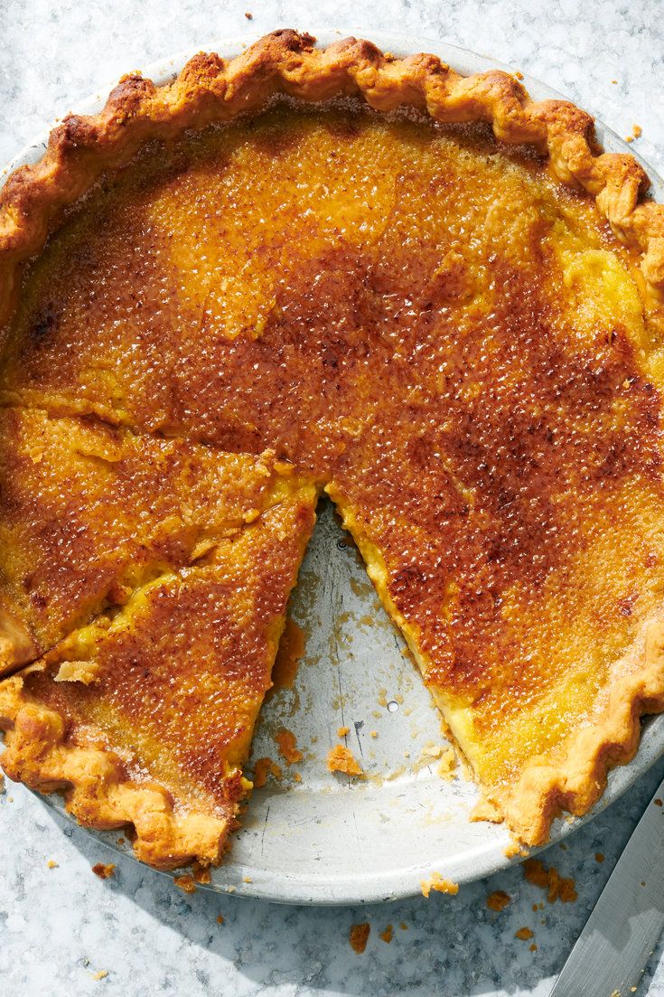 a pie sitting on top of a white plate next to a knife and fork in front of it