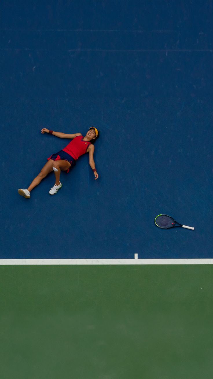 a tennis player laying on the court with her racquet in front of her