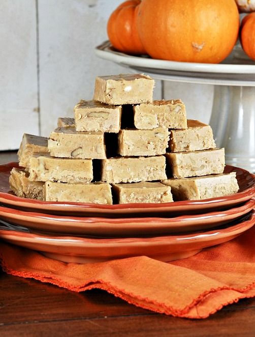 several pieces of brown fudge sitting on plates next to pumpkins