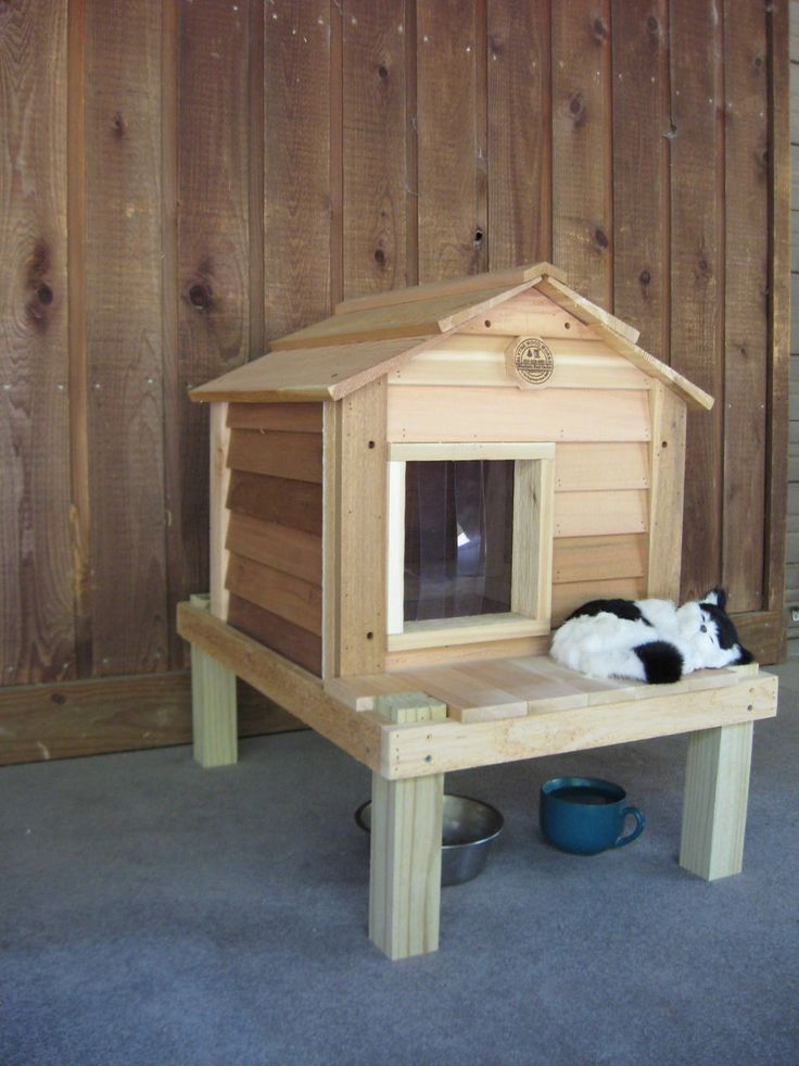 a black and white cat laying on top of a wooden house