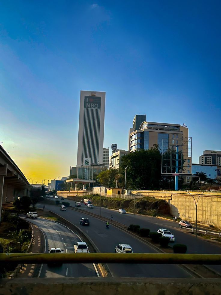 cars are driving down the highway in front of tall buildings