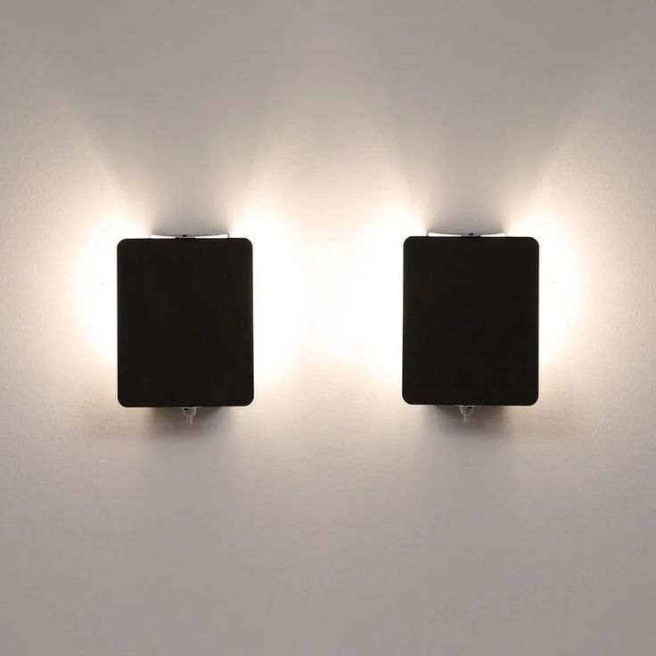 two square lights are on the wall in front of each other, one is black