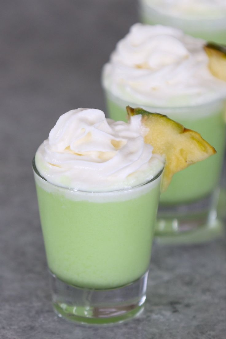 three glasses filled with green liquid and whipped cream