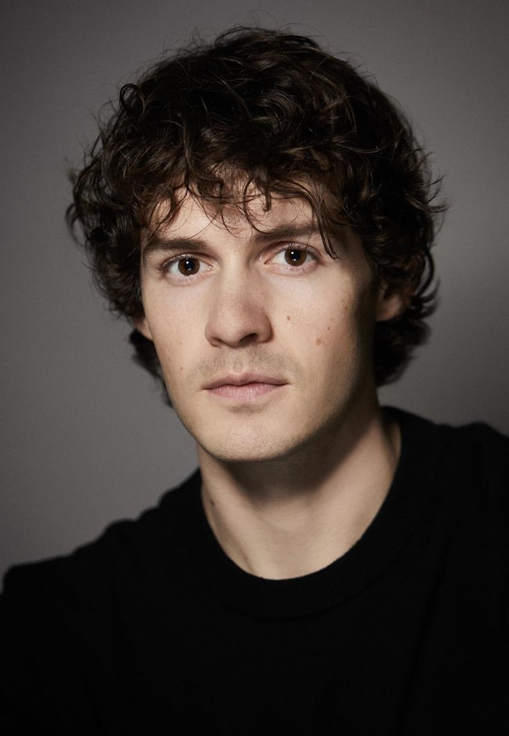 a close up of a person wearing a black shirt and looking at the camera with a serious look on his face