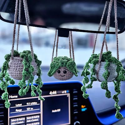 three crocheted balls hanging from the dashboard of a car with steering wheel controls