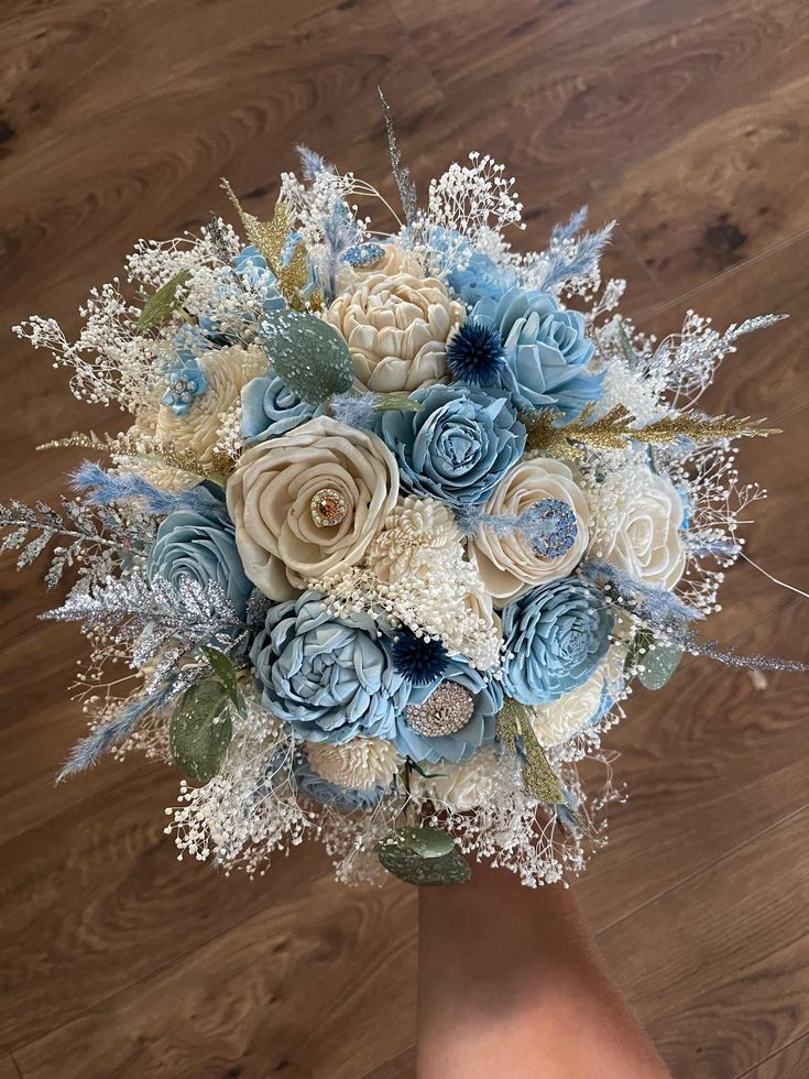 a bridal bouquet made up of blue and white flowers on top of a wooden floor