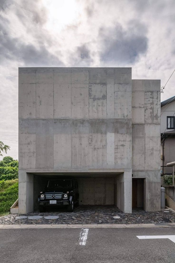 a car is parked in front of a concrete building that has been built into the ground