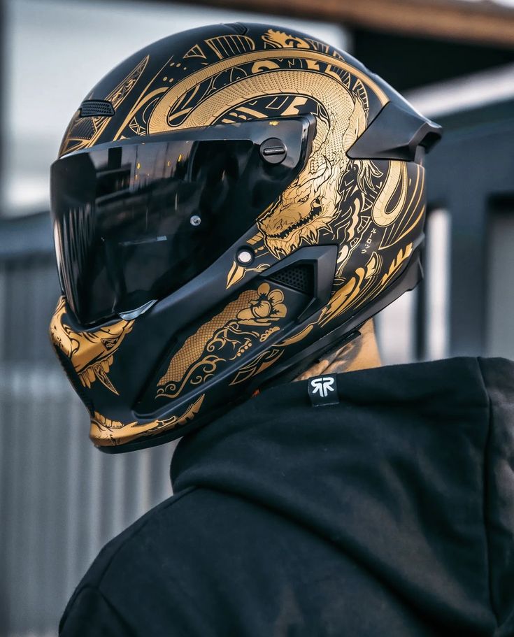 a person wearing a motorcycle helmet with gold dragon designs on the front and back of it