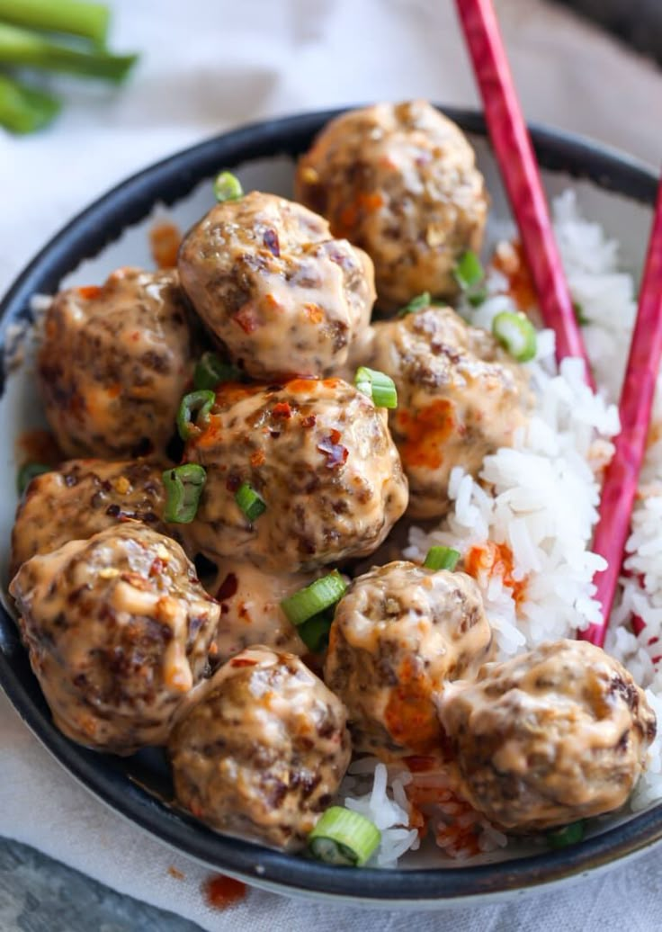 meatballs and rice in a bowl with chopsticks on the side for garnish