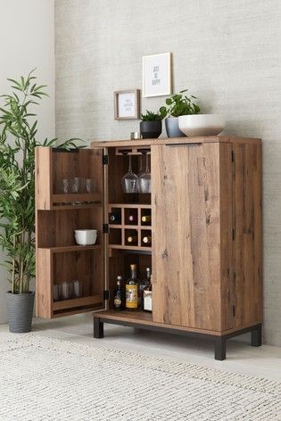 a wooden cabinet filled with lots of bottles and glasses next to a potted plant