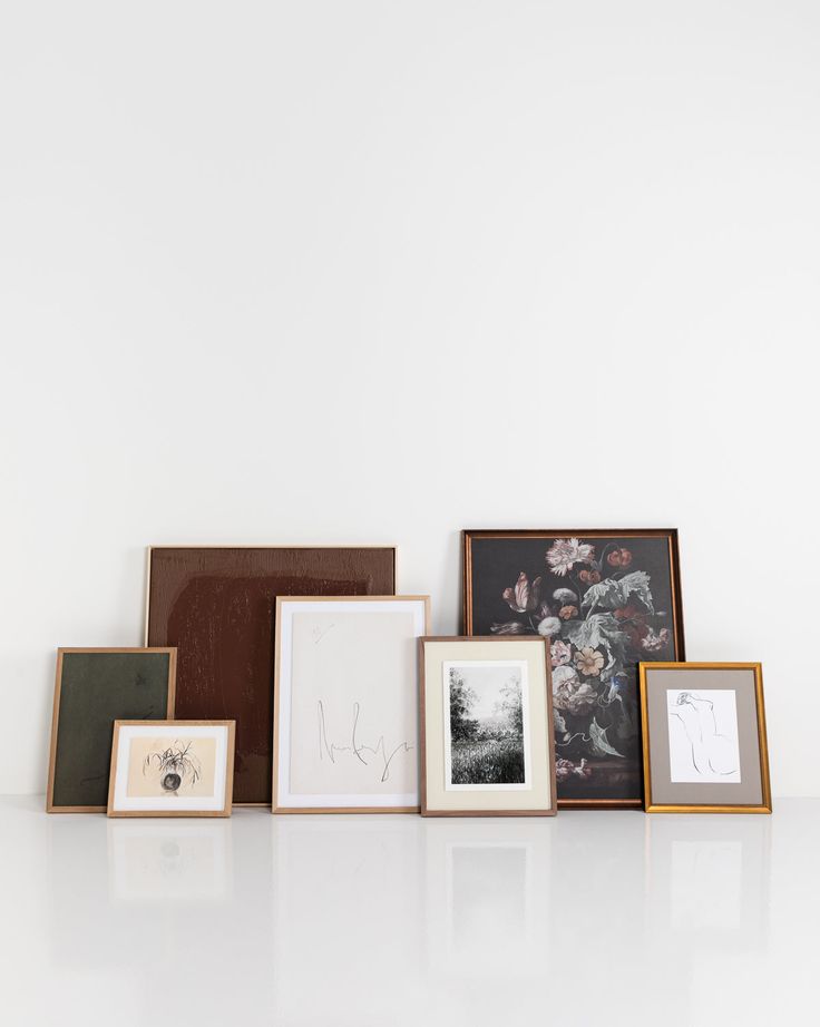 several different frames are lined up on a white surface, one is empty and the other has pictures