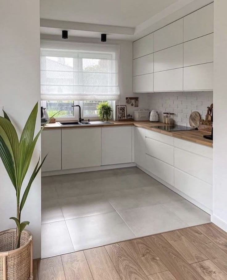 a kitchen with white cabinets and wooden floors