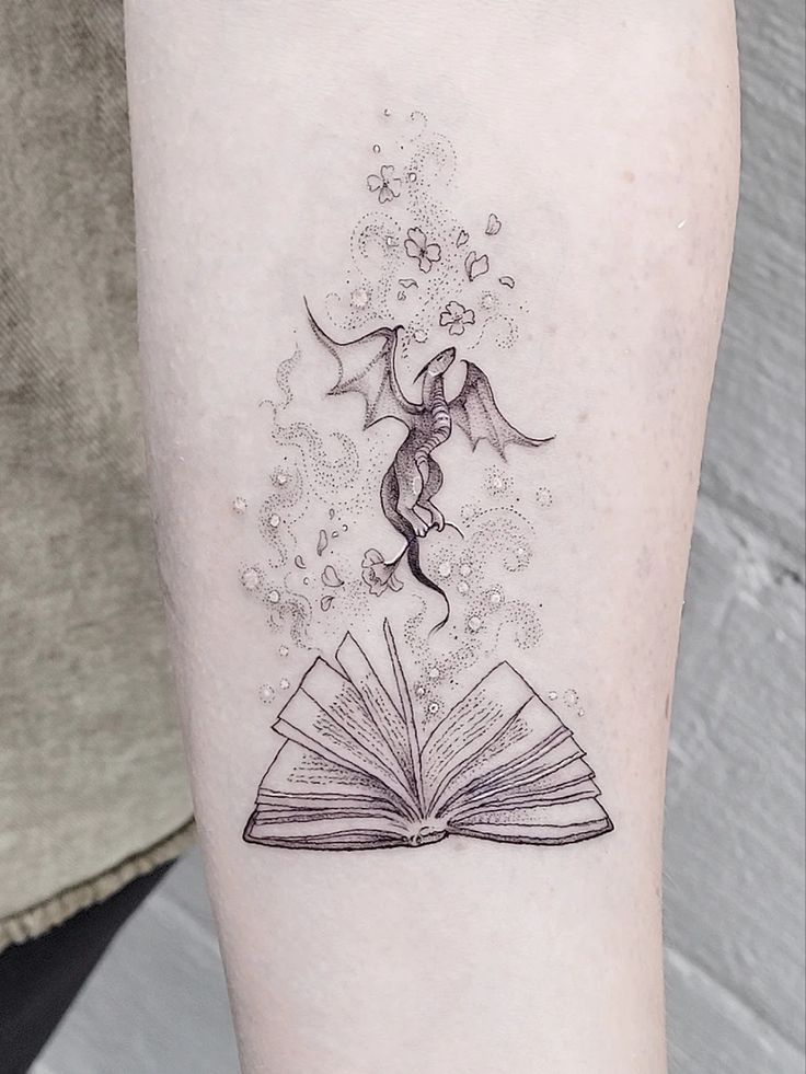 a woman's arm with an open book tattoo on it