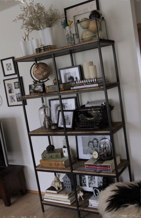 a bookshelf with pictures and other items on top of it in a living room