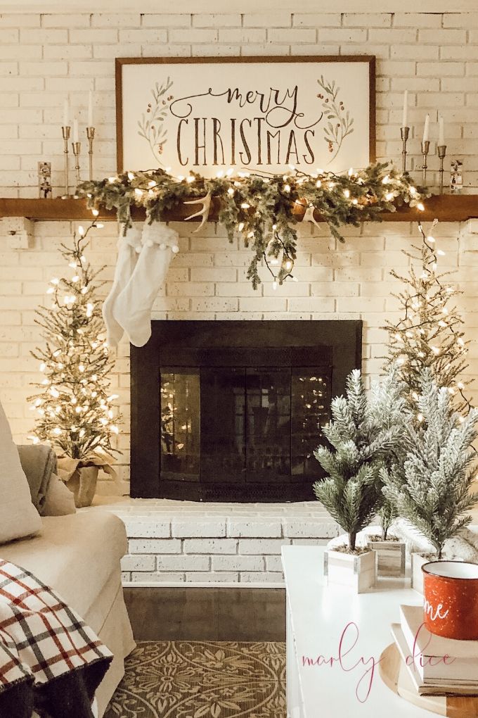 a living room decorated for christmas with stockings on the mantel and garlands hanging over the fireplace