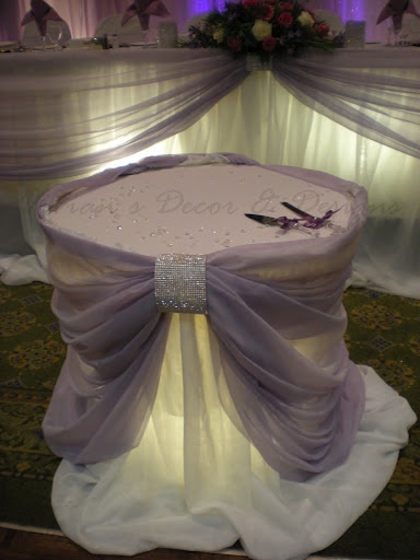 a white table topped with a bow on top of a chair covered in purple cloth