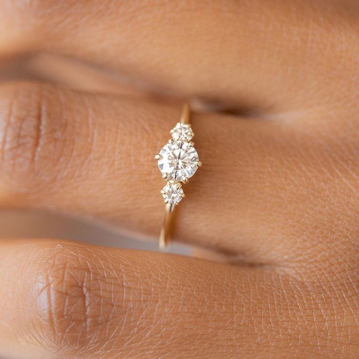 a woman's hand with a diamond ring on top of her left hand,