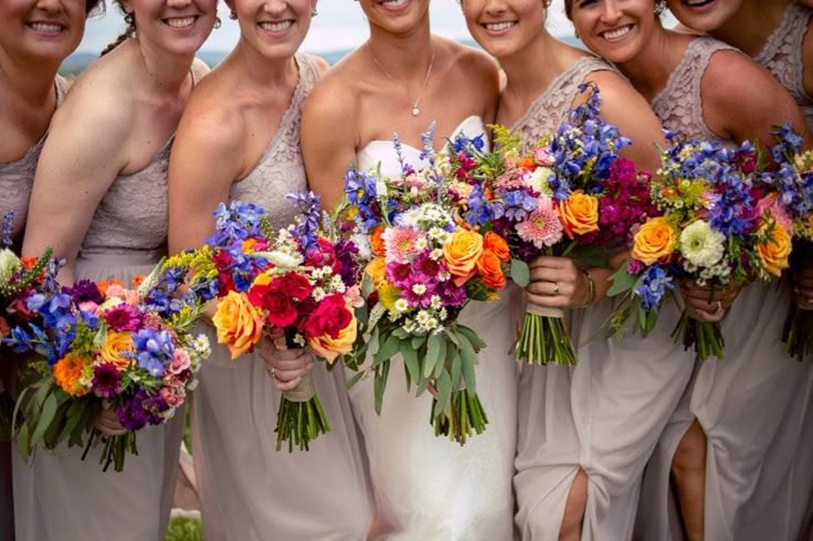 a group of women standing next to each other holding bouquets