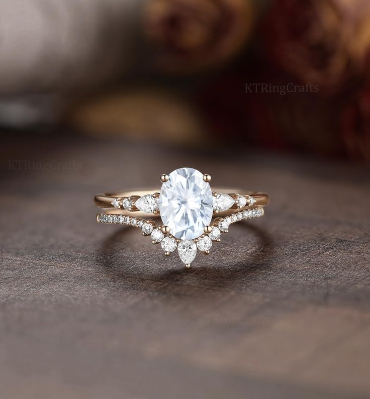 a close up of a diamond ring on a wooden table with roses in the background