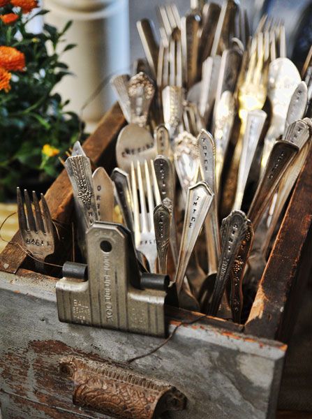 there are many forks and spoons in the box on the table next to flowers