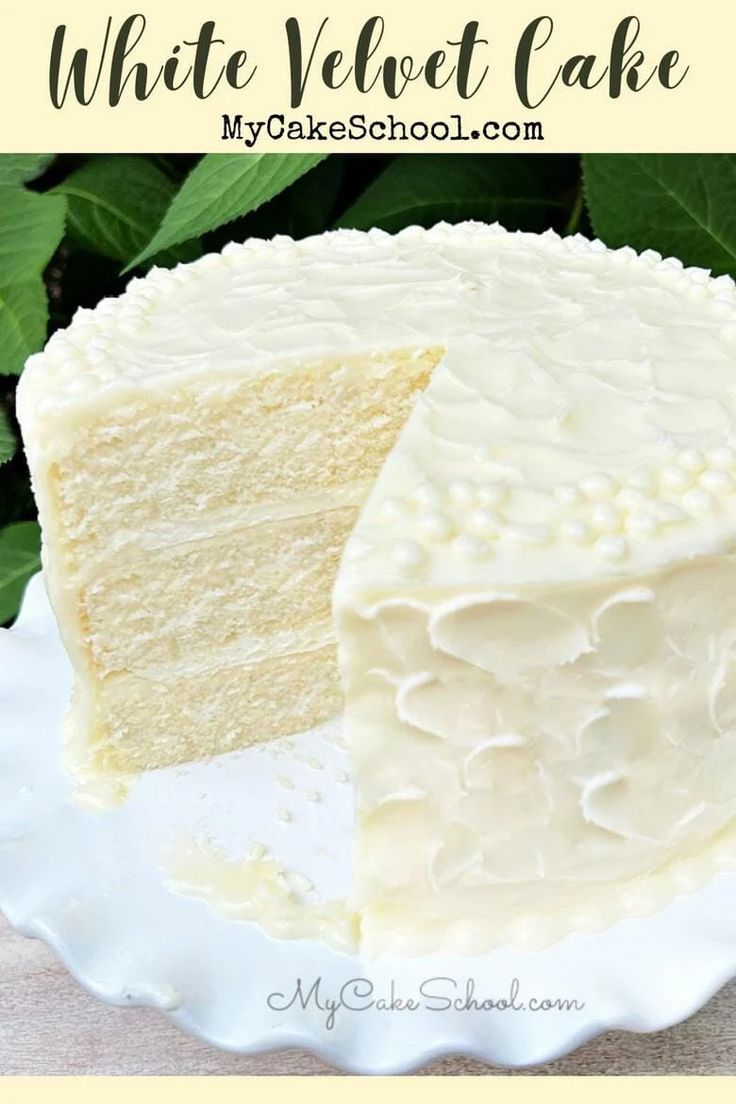 a white velvet cake on a plate with leaves in the background