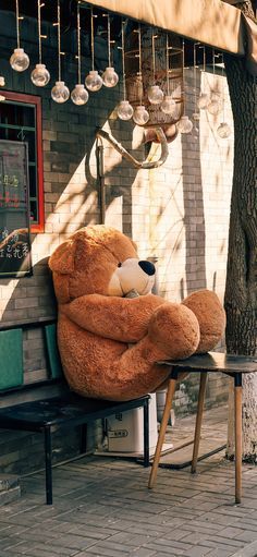 a large teddy bear sitting on top of a bench