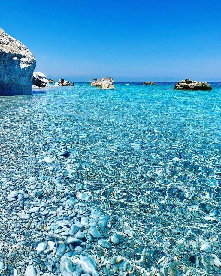 clear blue water with rocks in the background