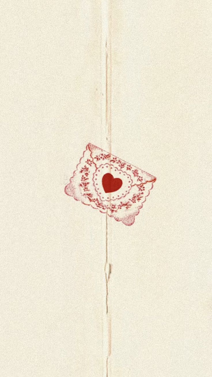 a piece of paper with a red heart on it and the corner of a wall