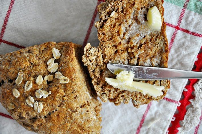 a close up of a piece of bread with butter and oats on it next to a knife