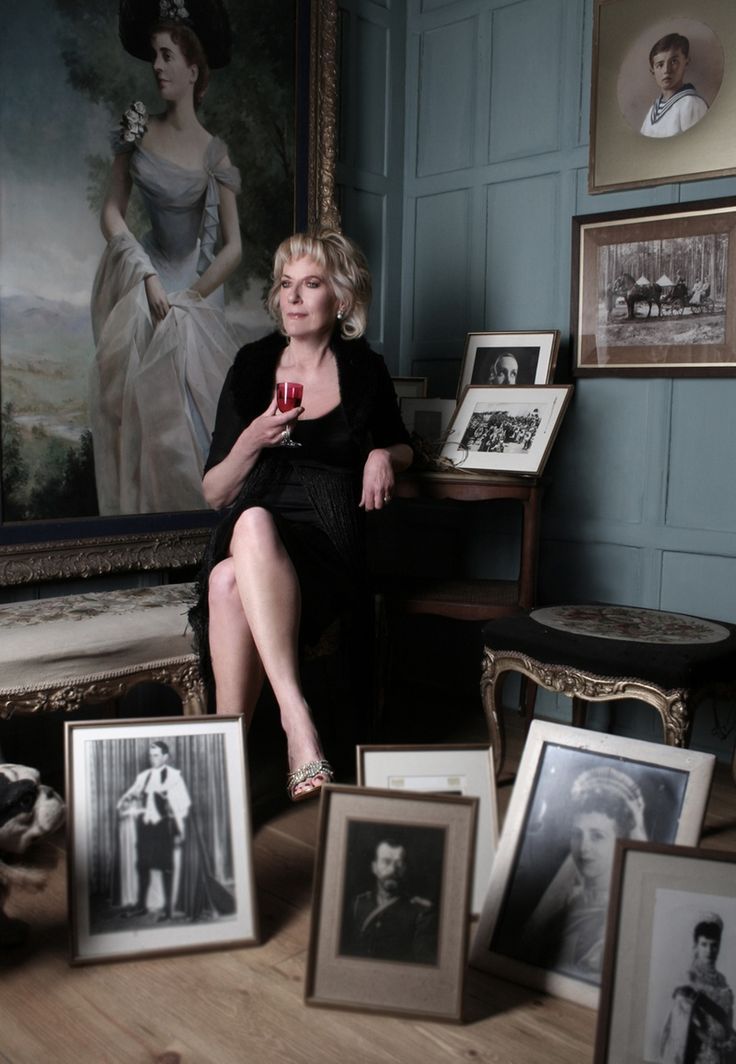 a woman sitting on a chair in front of some framed pictures and wineglasses