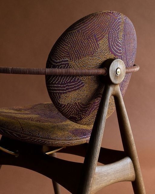 a wooden chair with an intricate design on the back and seat, against a brown background