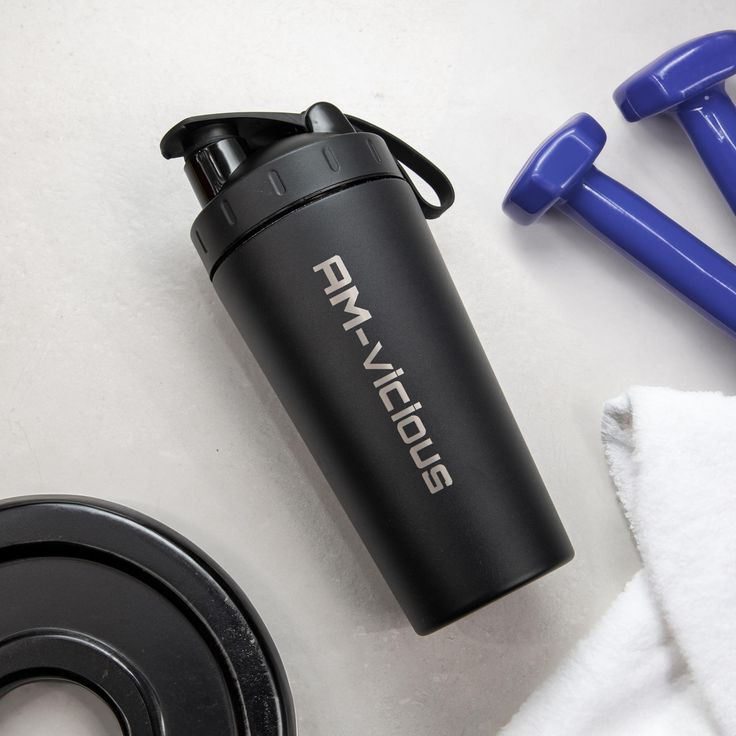 a black water bottle sitting on top of a white counter next to blue dumbbells