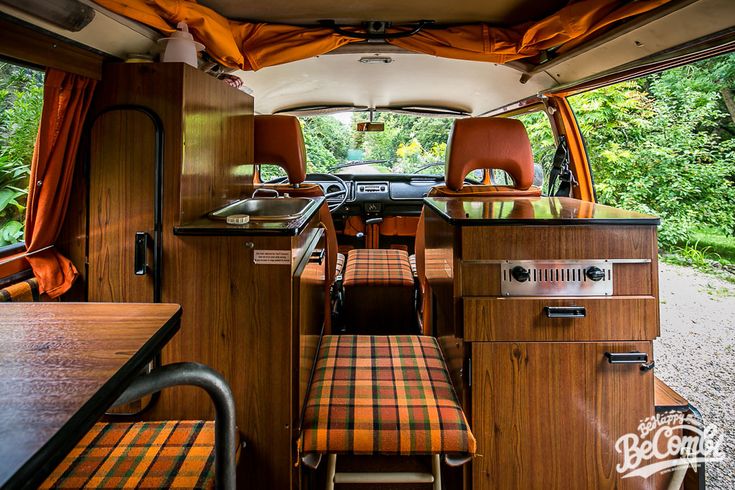 the interior of an rv with wood paneling and orange plaid upholstered seats