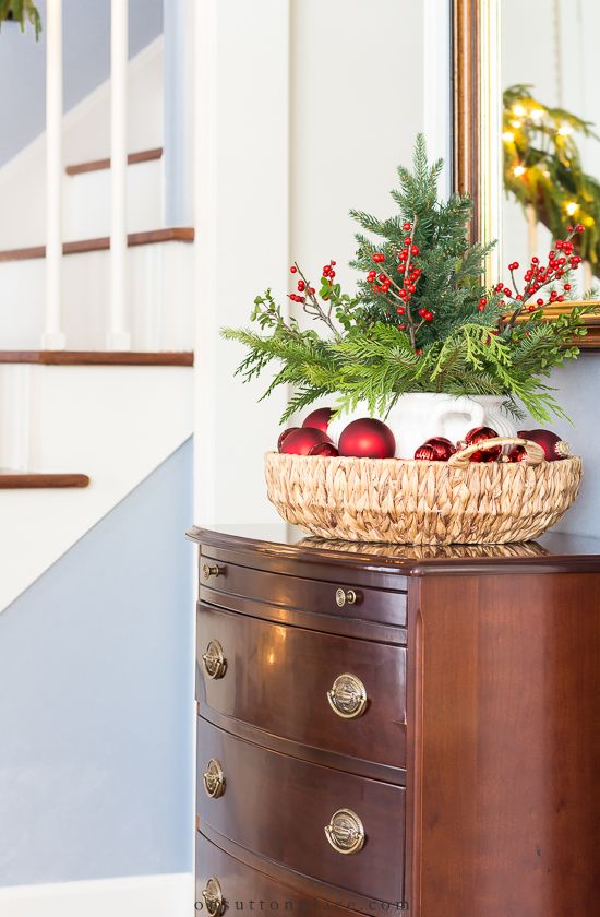 a basket filled with apples sitting on top of a dresser next to a christmas tree