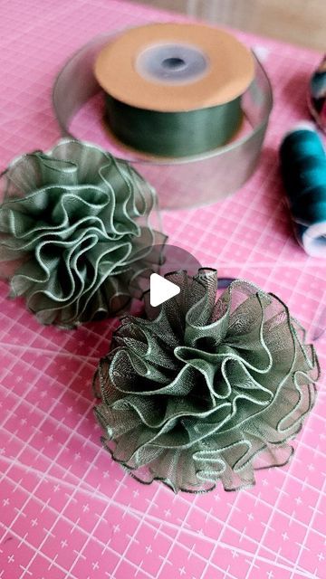 two green flowers sitting on top of a table next to spools of thread