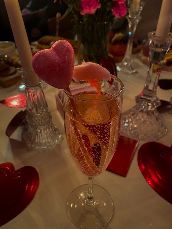 a wine glass filled with champagne and heart shaped candies