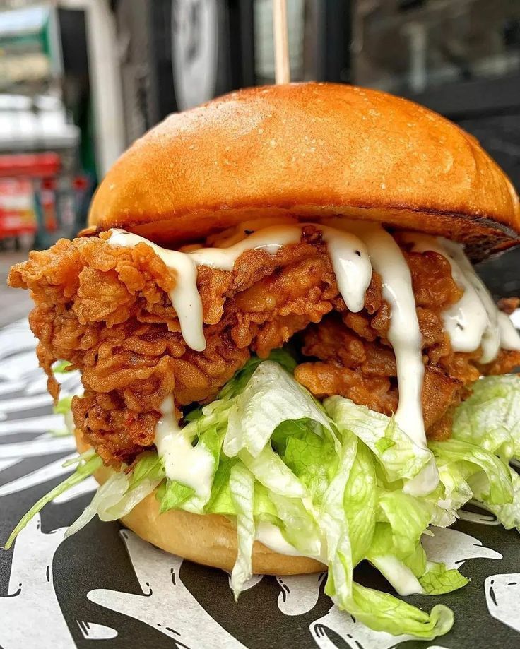 a fried chicken sandwich with lettuce and sauce