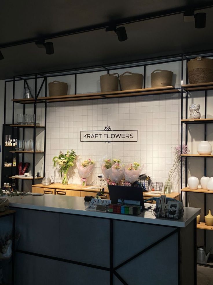 a flower shop with flowers on the counter and shelves full of potted plants behind it