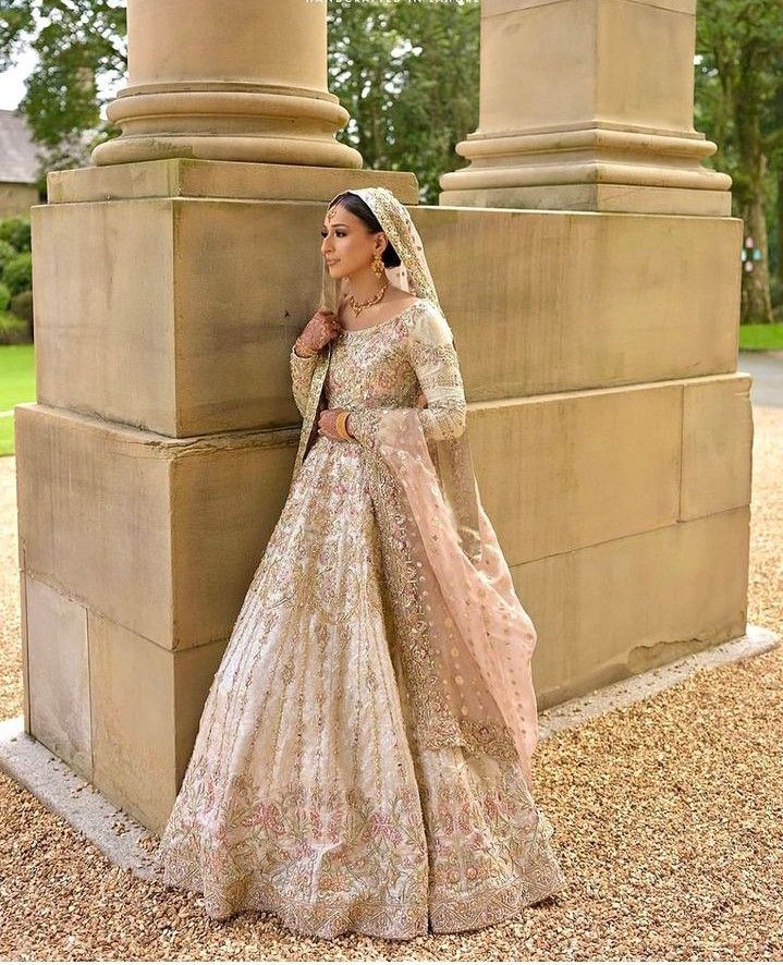 a woman in a wedding dress leaning against a pillar